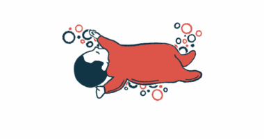 An infant in a red sleeper is seen napping.