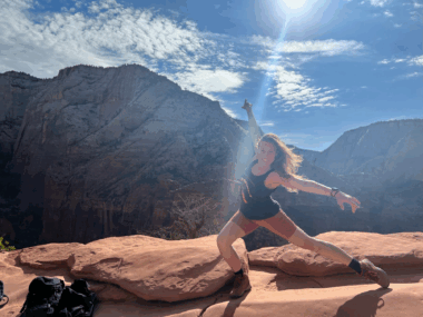 A woman is shown performing a dance move in front of a western landscape.