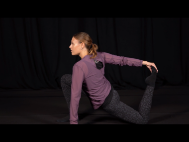A woman performs a dance move on a darkened stage.